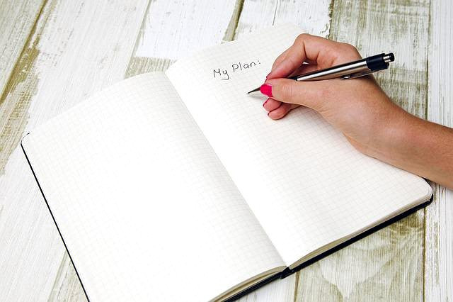 Eine Hand mit Stift schreibt in einem Tagebuch